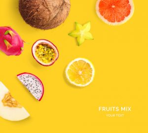 Creative layout made of lemon, grapefruit, pitahaya, passionfruit, melon, carambola and coconut. Flat lay. Food concept. Tropical fruits on the yellow background.