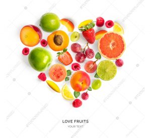 Creative layout with heart shape by various fruits. Heart of grape, apricot, raspberry, strawberry, lemon, apple, plum. Flat lay.