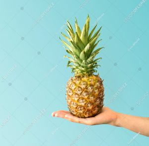 Hand holding a pineapple. Creative layout made of pineapple. Flat lay. Food concept.