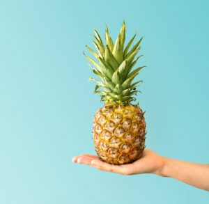 Hand holding a pineapple. Creative layout made of pineapple. Flat lay. Food concept.
