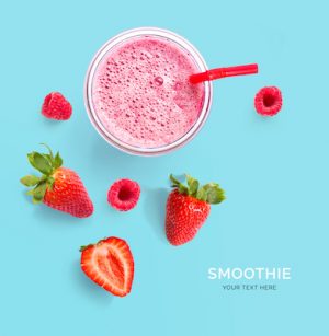 Creative layout made of raspberry, strawberry and coconut smoothie. Flat lay. Food concept. Smoothie on the blue background.