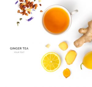 Creative layout made of cup of hot tea with ginger and lemon on a white background. Top view.