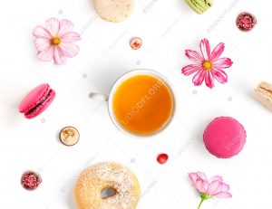 Creative layout made of tea, donuts, flowers and macaroons isolated on white background. Flat lay. Food concept.