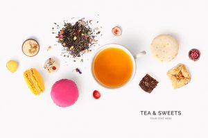 Creative layout made of tea, macaroons, praline on white background. Flat lay. Food concept.