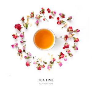 Creative layout made of cup of tea with flowers around  on a white background. Top view.