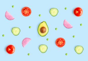 Creative layout made of green peas, avocado, tomato, onion and cucumber on the blue background.. Flat lay. Food concept.