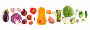 Creative layout made of green peas, cabbage, sweet potato, avocado, tomato, onion, beetroot, pepper, aubergine, artichoke, broccoli and cucumber on the white background.. Flat lay. Food concept.